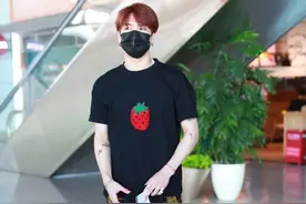 王嘉尔现身机场，穿搭黑色因草莓印花T，搭配法兰绒格子长裤图片