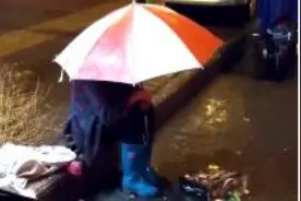 平顶山老奶奶坐地等环卫老爷爷下班，雨中撑伞犯困图片