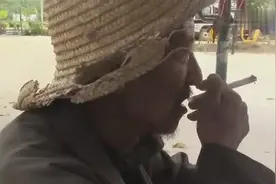 乡村老人在路边抽烟，卖的香烟不够劲，还是自己卷的好抽