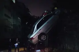 南宁一女司机倒车冲破围栏，将车挂在4米高墙上图片