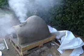 在后院用砖头搭建烤炉，几天后从里面取出美味的披萨饼图片