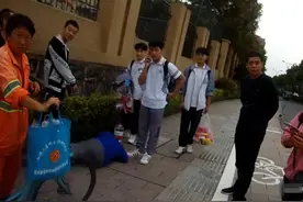 杭州一大伯酒后躺在路边，三校服男孩主动围在旁边当“安全警示桩”图片