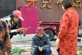 牙克石早市地摊，农民穿棉衣棉裤卖菜，一男子手机直播卖货图片