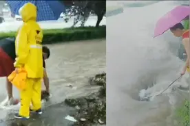 巩义强降雨致道路被积水淹没 父子俩撑伞在暴雨中疏通下水道图片