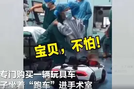 医院用玩具车接孩子进手术室，孩子坐在车上不愿下来图片
