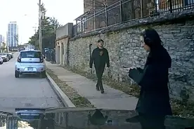 女子过马路玩手机没看到有车驶来 好心路人冲上前将她一把拉回图片