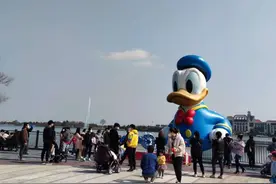 迪士尼小镇恢复开放的首个周六游客较多，家长们带着孩子在阳光下拍照、品美食图片