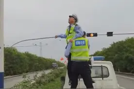 可爱！公路边悬挂的一面国旗卷到一起，交警“叠罗汉”让国旗迎风飘扬图片