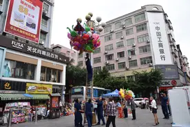 脑瘫男孩卖的气球飞上灯柱干着急，消防员爬高帮忙摘下图片