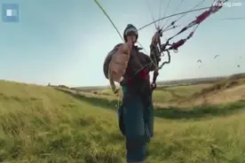英国一男子乘滑翔伞低空飞行 与地上的人一起踢足球图片