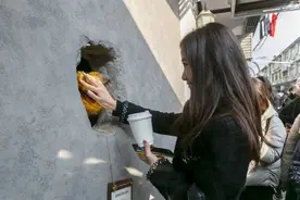 人们踮起脚尖，对着一个洞口，等待一只“熊爪”出现……图片