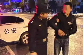 雪夜，醉汉睡在马路中间，民警轻拍想叫醒他，他嘴里咕哝着还不乐意图片