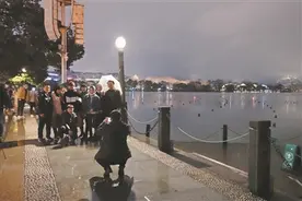 除夕夜的杭州市中心湖滨行人三五成群，酒吧生意不错 一个人坐在餐厅吃炸鸡，屏幕上一大家子人陪伴图片