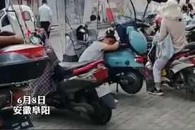 高考考场门口，下了夜班的妈妈趴在电动车上就睡着了……图片