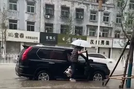 大雨路面积水严重，男子为不湿鞋上车用凳子自创“踩水神器”图片