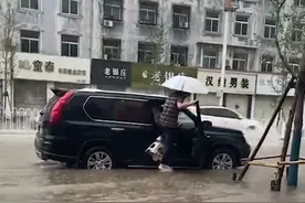 大雨路面积水严重，男子为不湿鞋上车用凳子自创“踩水神器”图片