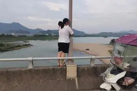女子抱着11个月大的婴儿，站在大桥栏杆外情绪激动……图片