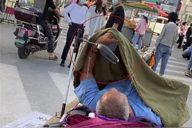 老夫妇郑州街头二维码乞讨，大妈坐着守摊，大爷被窝里玩手机图片