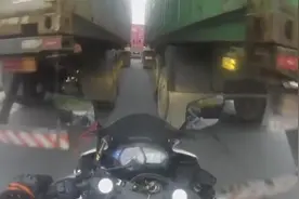 鲁莽！巴西摩托车手不愿等待从两卡车缝中穿行 车轮被卡车压扁图片