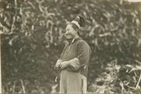 东北老照片：拿着烟管的满族女子和古老的满族特色建筑图片