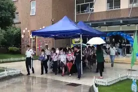 放学突然下雨，后勤叔叔扛起“移动城堡”护送千余名小学生出校园图片