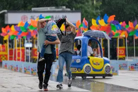 六一儿童节突降大雨，外出游玩的家长为孩子遮风挡雨图片