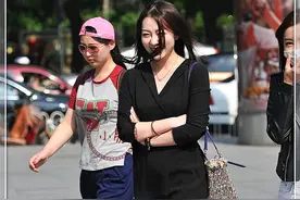 时尚街拍：气质辣妈穿着轻便小黑裙，抱着手走路，风采奕奕图片