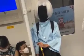 广东一女子乘地铁打扮怪异，手持手杖脸部全黑：一旁小孩紧盯着看图片