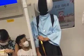 广东一女子乘地铁打扮怪异，手持手杖脸部全黑：一旁小孩紧盯着看图片