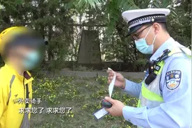 骑车人嫌天热将头盔“戴”在车牌上 被查后连忙求情：我求求你了