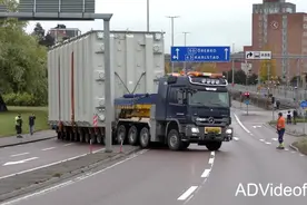 奔驰大件运输车满载大型货物艰难的通过市区街道。视频封面