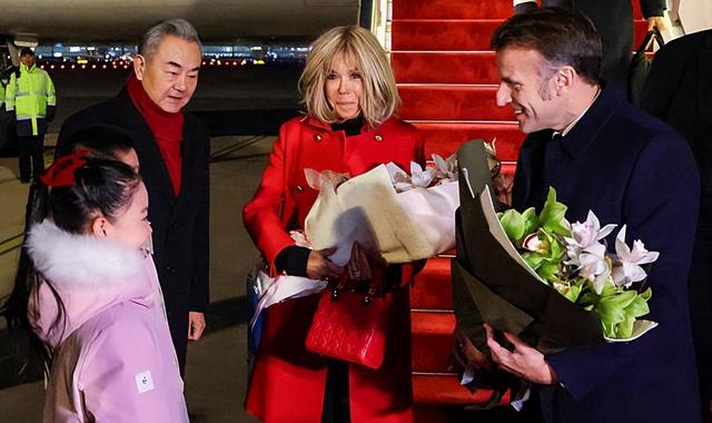 72岁法国第一夫人抵京惊艳	，红大衣配戴妃包超美