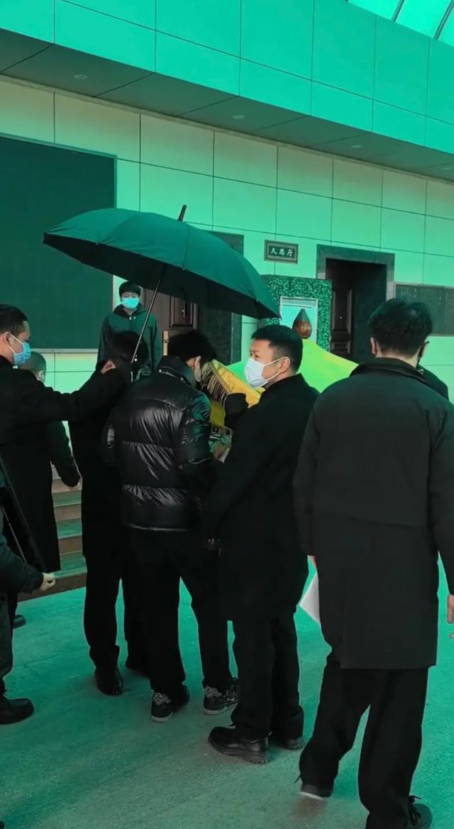 许何弯着腰抱着何晴遗像，背影很难过，许亚军没来给何晴撑伞！