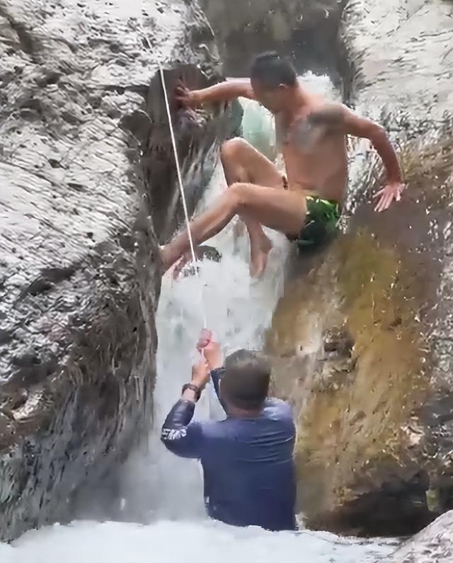 小男孩嬉水被卡两块巨石间，激流中反复挣扎难脱身，好心男子多次施救终成功