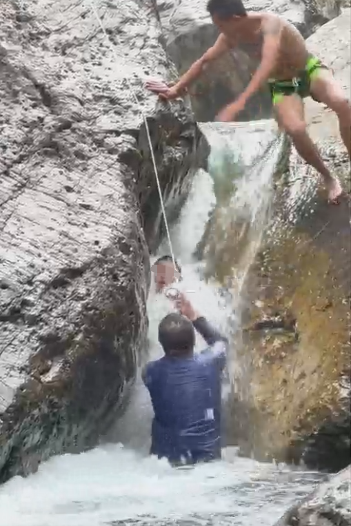 小男孩嬉水被卡两块巨石间，激流中反复挣扎难脱身，好心男子多次施救终成功