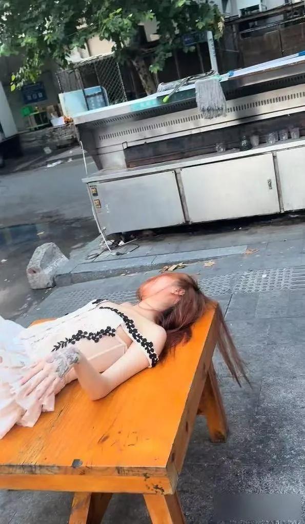 女子晚上喝得酩酊大醉，躺在烧烤摊的桌子上睡着了：天亮了还没醒