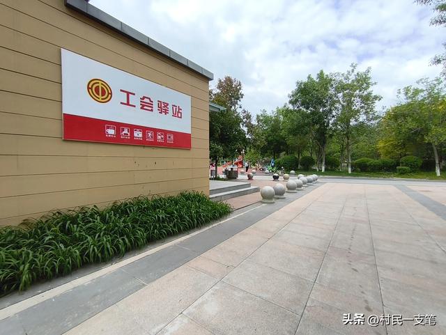 公园绿树成荫，路边花草芬芳，行人休闲漫步，享受快乐时光