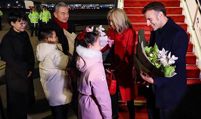 72岁法国第一夫人抵京惊艳	，红大衣配戴妃包超美