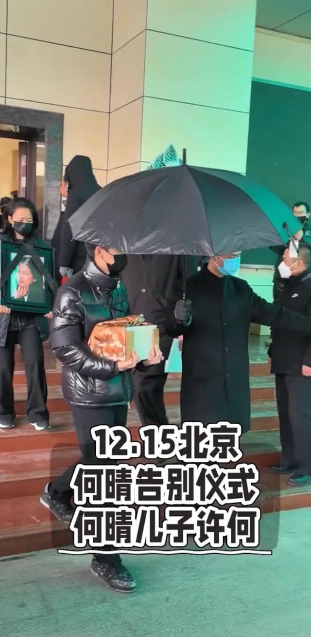 许何弯着腰抱着何晴遗像	，背影很难过，许亚军没来给何晴撑伞！