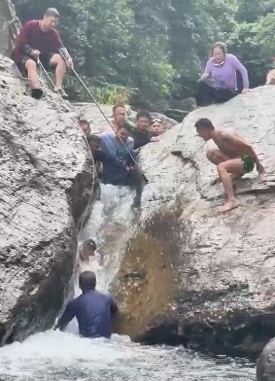 小男孩嬉水被卡两块巨石间，激流中反复挣扎难脱身，好心男子多次施救终成功