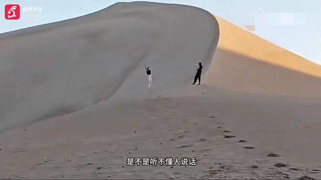 月牙泉景区游客无视喊话翻围栏拍照 围栏上就是警示牌