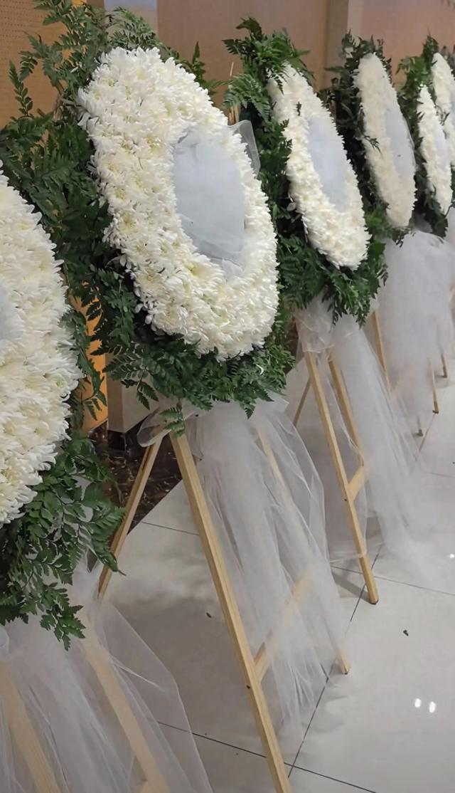 许何弯着腰抱着何晴遗像，背影很难过，许亚军没来给何晴撑伞！