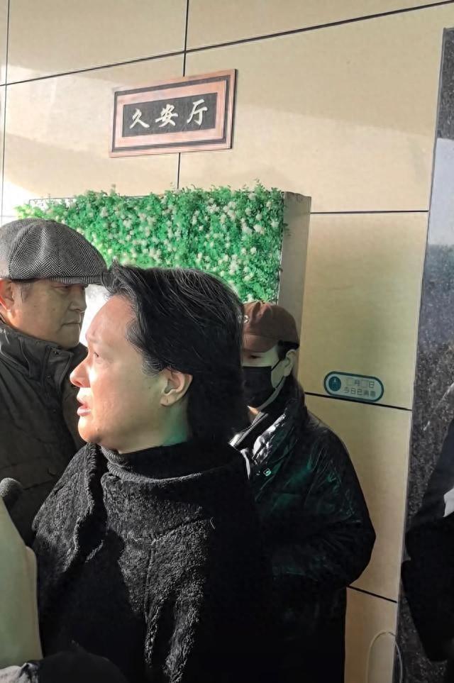 许何弯着腰抱着何晴遗像	，背影很难过，许亚军没来给何晴撑伞！