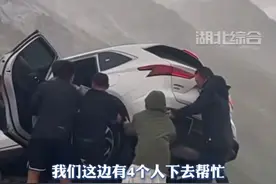 独库公路上一小车打滑至悬崖边，路过众人上前压住车尾救出两人