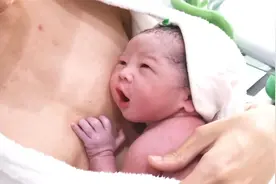 刚出生的小宝宝，被爸爸用喂奶的姿势抱着，接下来的表情亮了