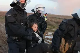 “环保少女”格蕾塔被男警察架着抬走，她双脚离地，面露笑容图片