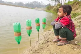 男孩在河边用塑料瓶鱼钩钓大鱼图片