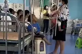 医院儿科内一位妈妈同时照看三个娃，双手举吊瓶，怀里还抱着老三图片