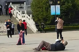 大爷躺地上找角度为大妈拍照，拍摄者：后面还有小情侣和一家三口，一段视频让爱情的3个阶段同框图片