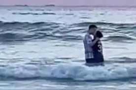 一对小情侣在海浪里拥吻，弥补了一群游客未看到日出的遗憾图片